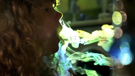 A-woman-blowing-smoke-rings-in-front-of-flashing-colored-lights