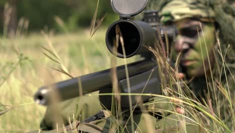 Sniper-soldier-lying-on-the-ground-and-camouflage-in-grass.-Soldier-holding-gun-weapon-and-waring-armor-uniform.-The-military-is-responsible-for-maintaining-the-territory.