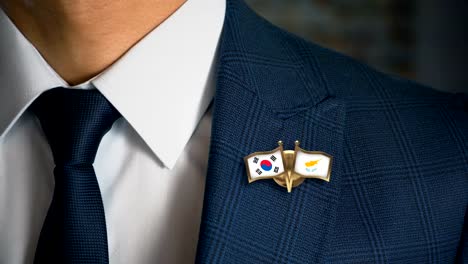 Geschäftsmann-zu-Fuß-in-Richtung-Kamera-mit-Freund-Land-Flaggen-Pin-Südkorea---Zypern