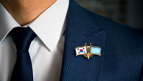 Geschäftsmann-zu-Fuß-in-Richtung-Kamera-mit-Freund-Land-Flaggen-Pin-Südkorea---Mikronesien