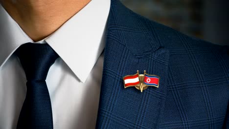 Geschäftsmann-zu-Fuß-in-Richtung-Kamera-mit-Freund-Flaggen-Pin-Österreich---Nordkorea