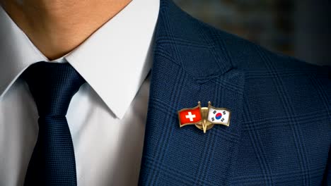 Geschäftsmann-zu-Fuß-in-Richtung-Kamera-mit-Freund-Flaggen-Pin-Schweiz---Südkorea