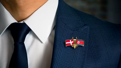 Geschäftsmann-zu-Fuß-in-Richtung-Kamera-mit-Freund-Flaggen-Pin-Dänemark---Nordkorea