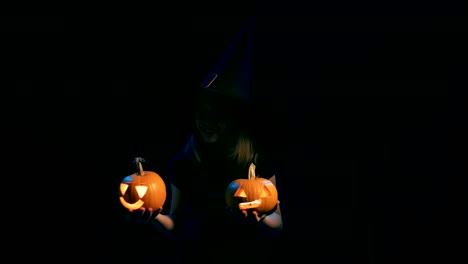 Girl-wearing-black-witch-hat-holding-jack-o'-lanterns