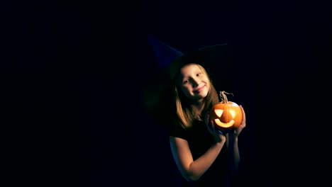 Girl-wearing-black-witch-hat-holding-jack-o'-lanterns