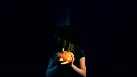 Girl-wearing-black-witch-hat-holding-jack-o'-lanterns