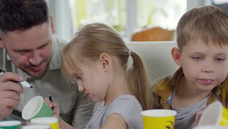 Kleinen-Bruder-und-Schwester-machen-Party-Cups-mit-Papa