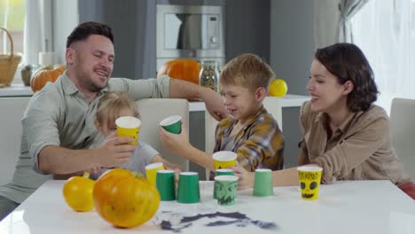 Glückliche-Familie-mit-Halloween-Cups-spielen