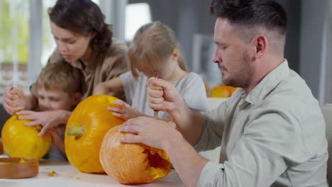 Hombre-sonriente-a-la-cámara-mientras-hacer-calabazas-de-Halloween-juntos