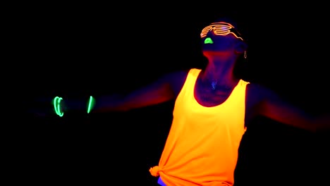 Woman-with-UV-face-paint,-glowing-clothing,-glowing-glasses,-bracelet-dancing-in-front-of-camera,-half-body-shot.-Asian-woman.-.