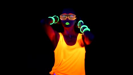 Woman-with-UV-face-paint,-glowing-clothing,-glowing-glasses,-bracelet-dancing-in-front-of-camera,-half-body-shot.-Asian-woman.-.