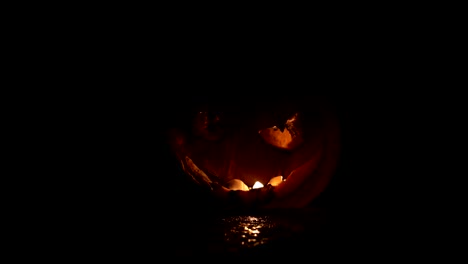 Horror-Halloween-concept.-Close-up-view-of-scary-dead-Halloween-pumpkin-glowing-at-dark-background.-Rotten-pumpkin-head.-Selective-focus