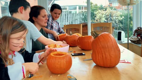 Junge-Familie-schnitzen-Kürbisse-für-Halloween