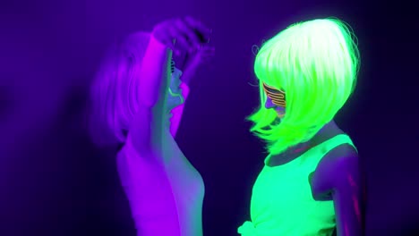 Langsame-Motin-von-schönen-sexy-Frauen-mit-fluoreszierenden-Make-up-und-Kleidung-Tanz-im-Neonlicht.-Night-Club,-Party-Konzept.