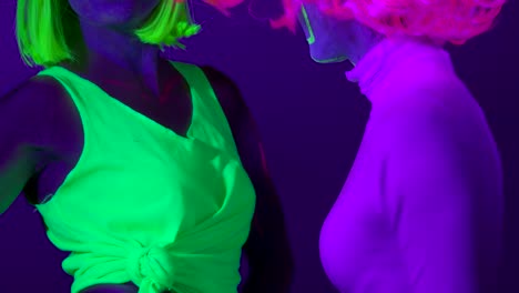 Langsame-Motin-von-schönen-sexy-Frauen-mit-fluoreszierenden-Make-up-und-Kleidung-Tanz-im-Neonlicht.-Night-Club,-Party-Konzept.