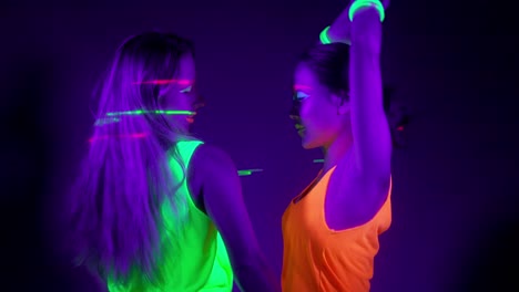 Langsame-Motin-von-schönen-sexy-Frauen-mit-fluoreszierenden-Make-up-und-Kleidung-Tanz-im-Neonlicht.-Night-Club,-Party-Konzept.