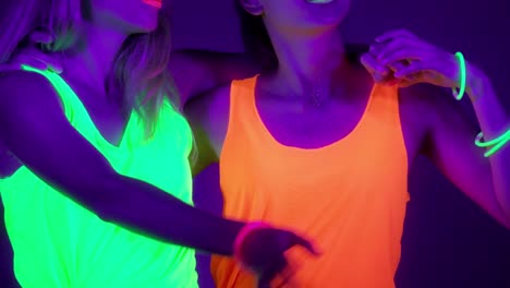 Langsame-Motin-von-schönen-sexy-Frauen-mit-fluoreszierenden-Make-up-und-Kleidung-Tanz-im-Neonlicht.-Night-Club,-Party-Konzept.