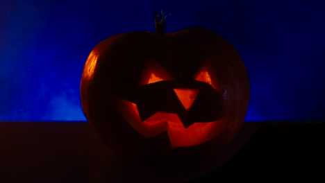 CINEMAGRAPH---CU-Halloween-tallado-CALABAZA-Jack-o-Lantern-con-velas,-niebla-en-el-fondo