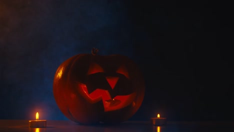 CINEMAGRAMM---CU-Halloween-geschnitzten-Kürbis-Jack-o-Laterne-mit-Kerzen,-Nebel-im-Hintergrund