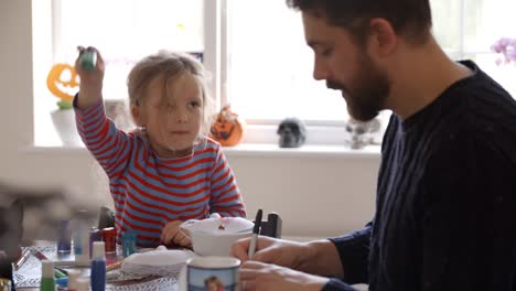 Padre-e-hija-haciendo-máscaras-de-Halloween-en-casa-juntos