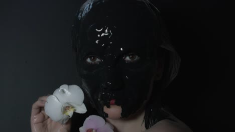 4k-shoot-of-a-horror-Halloween-model---Crazy-girl-in-black-mud-with-flower