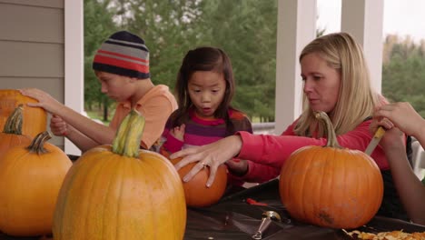 Mom-and-kids-carving-pumpkins-for-Halloween