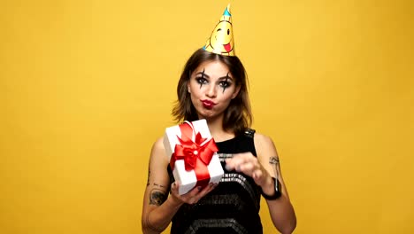 Displeased-strange-woman-with-holiday-cap-throwing-gift-isolated-over-yellow