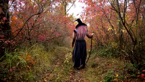 Young-pink-hair-witch-in-hat-search-reagents-in-the-mystical-autumn-forest.-Halloween-soon.