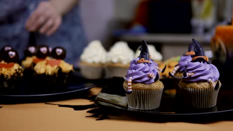 Cupcake-mit-Hut-und-Beine-Puderzucker-dekorieren.-Muffin-wie-Hexe.-Halloween-Konzept