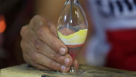 Man-shows-his-skills,-creating-a-souvenir-of-colored-sand-in-glass-vase.-Egypt