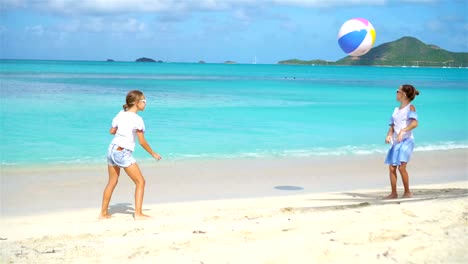 Kleinen-niedlichen-Mädchen-spielen-mit-Kugel-am-Strand