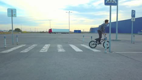 flying-4k-shot-of-young-teenager-in-casual-doing-a-jump-trick-on-a-bmx-bike-going-on-a-street-crosswalk-in-the-city