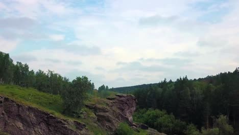 Ein-Sniper-mit-einem-Gewehr-sitzt-oben-auf-dem-Berg-und-inspiziert-das-Gebiet.-Blick-von-der-Drohne.-die-Kamera-bewegt-sich-zu-den-Soldaten,-offenbart-einen-Blick-auf-die-Landschaft