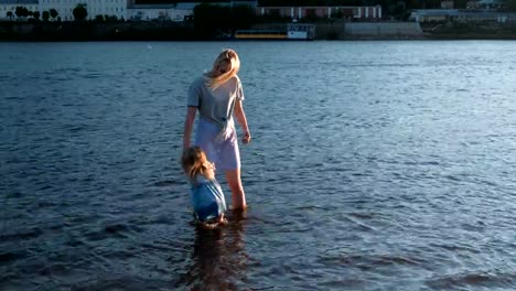 Mom-and-girl-playing-on-the-beach-of-the-river-at-sunset-and-swim.