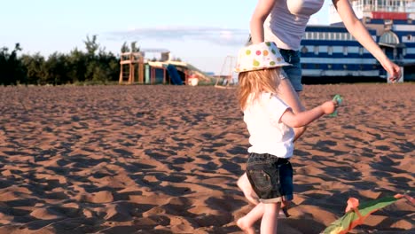 Schöne-Blondine-in-einem-Hut-Mutter-und-Tochter-startet-einen-Kite-am-Strand.