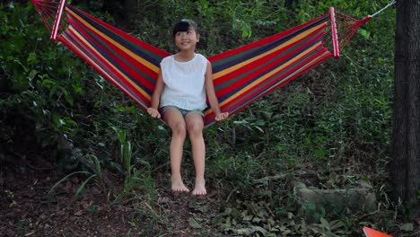 Little-girl-resting-lying-on-hammock-outdoors-in-slow-motion