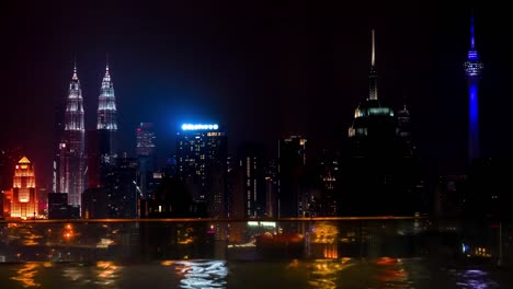 Swiming-pool-on-the-edge-of-rooftop-and-night-cityscape-of-Kuala-Lumpur,-Malaysia-Timelapse-4K