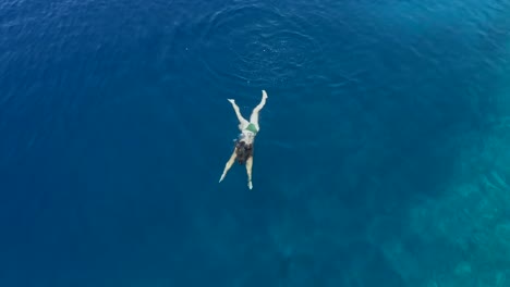 Luftaufnahmen-von-einem-Mädchen-schwimmen-im-blauen-Meer