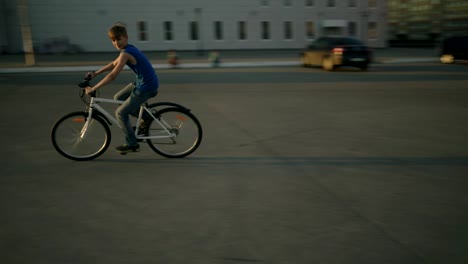 Un-lindo-niño-preadolescente-paseos-en-bicicleta-en-círculos-alrededor-de-la-cámara-en-una-ciudad