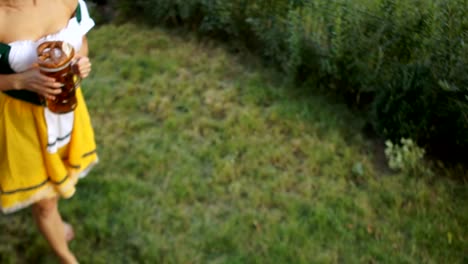 Waitress-at-the-music-festival-Oktoberfest-in-Germany.-A-girl-in-a-Bavarian-suit-walks-the-grass-and-carries-beer-to-customers