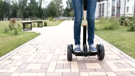 Mujer-morena-está-rodando-en-scooter-de-giro-cerca-de-la-casa,-nuevo-vista.-Piernas-de-primer-plano.