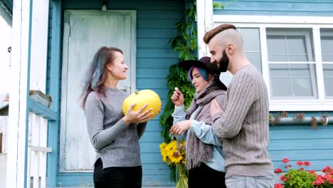 Three-people-in-background-of-village-house-on-farm-talk-and-laugh.