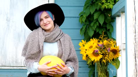 A-young-beautiful-woman-is-sitting-on-porch-of-country-house-with-pumpkins.