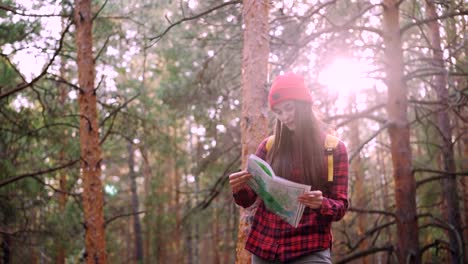 Happy-tourist-attractive-young-woman-is-travelling-in-forest-then-looking-at-map-and-looking-around-exploring-wood.-Adventurous-people,-happiness-and-sunlight-concept.