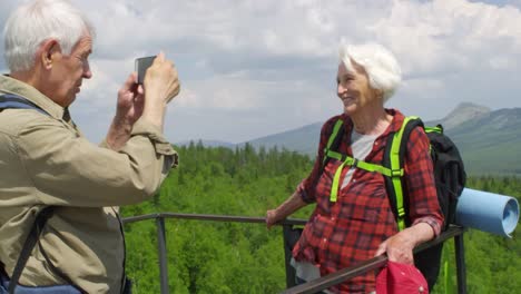 Senior-Hikers-Photographing-at-the-Top-on-Mountain