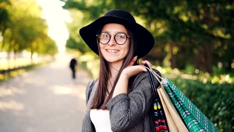 Portrait-of-cheerful-girl-shopper-posing-with-paper-bags,-looking-at-camera,-smiling-and-laughing-standing-in-the-street-in-big-city.-Youth-and-shopping-concept.