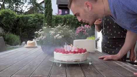 Hombre-joven-sopla-las-velas-de-cumpleaños