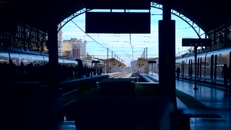 En-la-estación-de-ferrocarril,-muchos-pasajeros-en-una-plataforma-están-esperando-su-tren