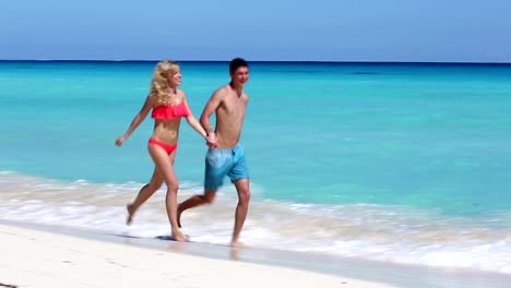 Young-couple-running--on-caribbean-beach