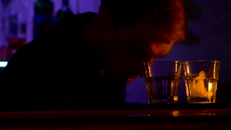 Young-bartender-making-tricks-with-two-glasses-and-puts-ice--standing-behind-the-bar,-shots,-slow-motion